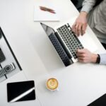 person using laptop on white wooden table